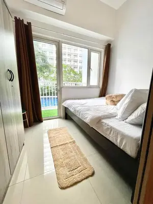 a bedroom with a bed and a window and a rug at Direct Pool Access in Shore Residences near SM MOA in Manila