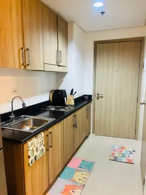 a kitchen with wooden cabinets and a sink and a door at Direct Pool Access in Shore Residences near SM MOA in Manila