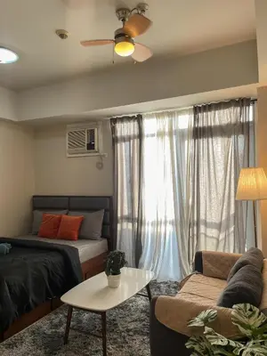 a living room with a bed and a couch at Cozy Manhattan Araneta Cubao in Manila