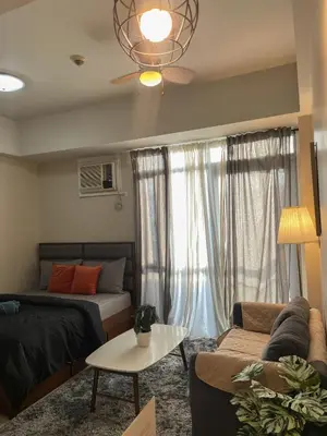 a living room with a bed and a couch at Cozy Manhattan Araneta Cubao in Manila