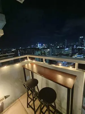 a table and two chairs on a balcony at night at Cozy Manhattan Araneta Cubao in Manila