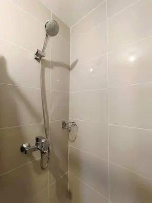 a shower with a shower head in a bathroom at Cozy Manhattan Heights 1 Bedroom Araneta Cubao in Manila