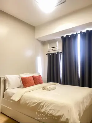 a bedroom with a bed with blue curtains at Cozy Manhattan Heights 1 Bedroom Araneta Cubao in Manila