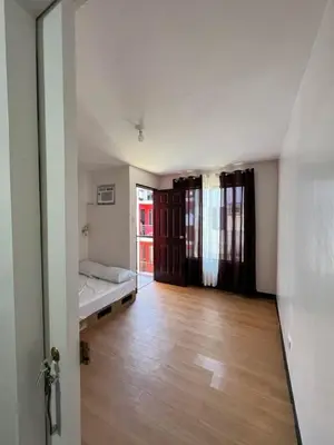 a bedroom with a bed and a wooden floor at Cozy Condo for Relaxing Stays & Movie Nights in Imus
