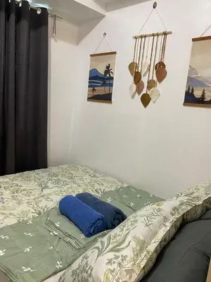 a bed with a blue pillow and pictures on the wall at Stern Home Stay at Sea Residences in Manila