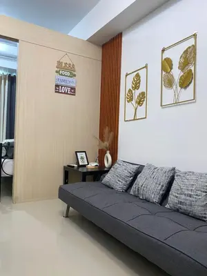 a living room with a couch and a sign on the wall at Stern Home Stay at Sea Residences in Manila