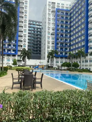 a patio with tables and chairs in front of some buildings at Stern Home Stay at Sea Residences in Manila