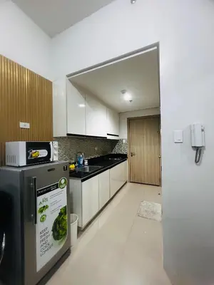 a kitchen with white cabinets and a refrigerator at Cozy Staycation at Shore Residences near Mall Of Asia MOA in Manila