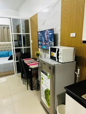 a kitchen with a table and a tv in a room at Cozy Staycation at Shore Residences near Mall Of Asia MOA in Manila