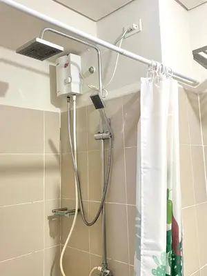 a shower head in a bathroom with a shower curtain at 1BR Cozy Minimalist Unit near MOA or Manila Bay in Manila