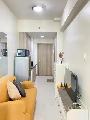 a living room with a yellow couch and a tv at 1BR Cozy Minimalist Unit near MOA or Manila Bay in Manila
