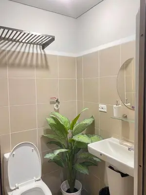 a bathroom with a toilet and a sink and a plant at 1BR Cozy Minimalist Unit near MOA or Manila Bay in Manila