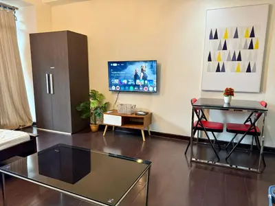 a living room with a glass table and a tv at The Gramercy Residences Executive 1 bedroom with Balcony in Manila