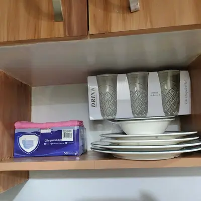 a shelf with plates and cups and a box at Fully Furnished Condo at Cyberzone-Filinvest in Manila