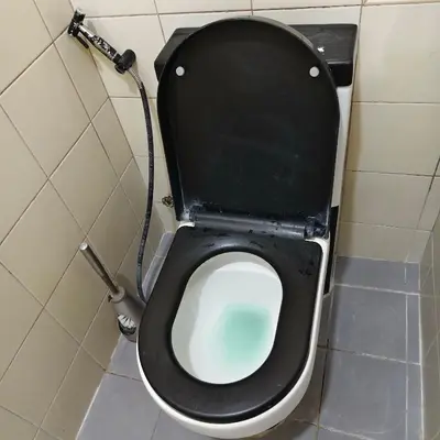 a toilet with a black seat and a hose at Fully Furnished Condo at Cyberzone-Filinvest in Manila