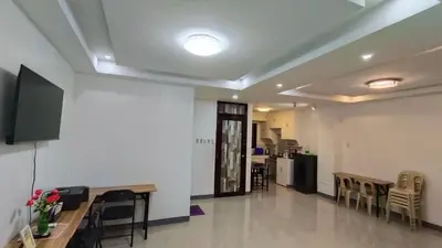 a living room with tables and chairs and a kitchen at Makati 2C Suite Room in Manila