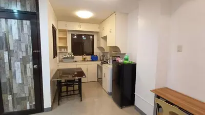a small kitchen with a black refrigerator and a table at Makati 2C Suite Room in Manila