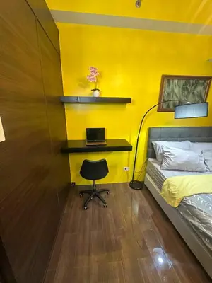 a bedroom with a bed and a desk with a laptop at Sunbeam - Air Residence 42nd floor in Manila