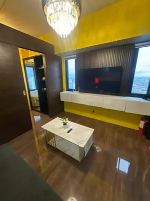 a living room with a table and a television at Sunbeam - Air Residence 42nd floor in Manila