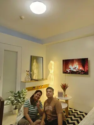 a man and woman sitting in a living room with a fireplace at Shore residences Yen and Yan Staycation in Manila