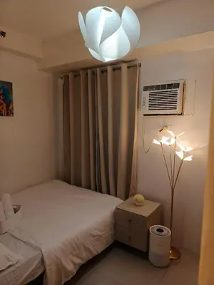 a bedroom with a bed and a chandelier at Shore residences Yen and Yan Staycation in Manila