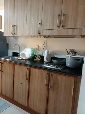 a kitchen with wooden cabinets and a sink and a counter at Shore residences Yen and Yan Staycation in Manila