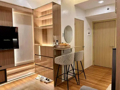 a kitchen with a bar and two stools in a room at GRACE RESIDENCES Condo in Manila