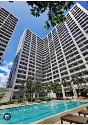 a large building with a swimming pool in front of it at GRACE RESIDENCES Condo in Manila