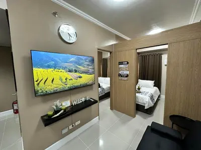 a hotel room with a tv on the wall and a bedroom at 2 BR Fully Furnished Condo in Parañaque with Pool and Parking - Bloom Unit 1133 in Manila
