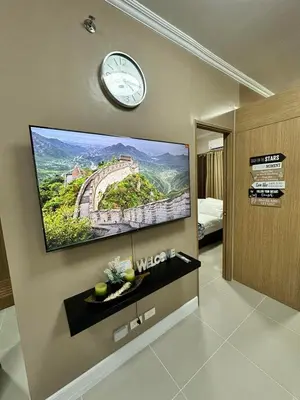 a flat screen tv on a wall with a clock at 2 BR Fully Furnished Condo in Parañaque with Pool and Parking - Bloom Unit 1133 in Manila