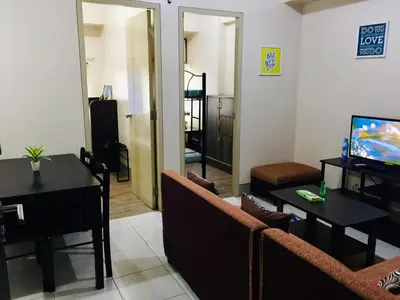 a living room with a couch and a table and a television at Little Baguio Terraces in Manila