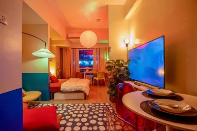 a living room with a large television and a bedroom at Modern Studio with Balcony near Ayala Makati in Manila