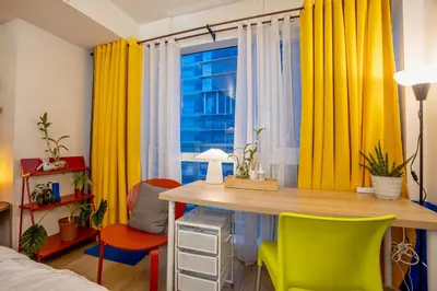 a bedroom with yellow curtains and a desk and chairs at Modern Studio with Balcony near Ayala Makati in Manila