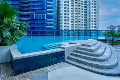 a large swimming pool with stairs in a city at Modern Studio with Balcony near Ayala Makati in Manila
