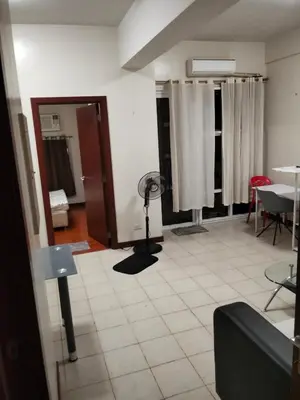 a living room with a fan in the middle of a room at Paseo de Roces Condominium in Manila
