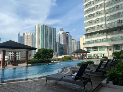 a swimming pool with chairs and umbrellas in a city at 2 Bedroom Premium Condominium Beacon Makati in Manila