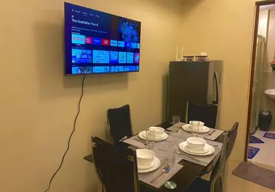 a table with chairs and a television hanging on a wall at 2 Bedroom Premium Condominium Beacon Makati in Manila
