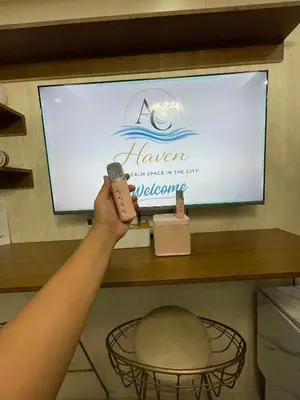 a person holding a microphone in front of a television at AC Haven in Shore Residences near MOA Pasay City in Manila
