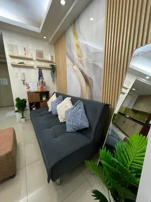 a living room with a blue couch with pillows at AC Haven in Shore Residences near MOA Pasay City in Manila