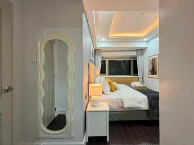 a bedroom with a large bed and a mirror at Premier 3BR with Fast Internet near High Street BGC in Manila