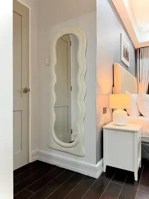 a mirror in a bedroom with a bed and a table at Premier 3BR with Fast Internet near High Street BGC in Manila