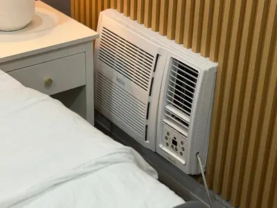 a room with a air conditioner on a wall next to a bed at Premier 3BR with Fast Internet near High Street BGC in Manila