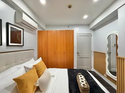 a bedroom with a bed and a wooden cabinet at Premier 3BR with Fast Internet near High Street BGC in Manila