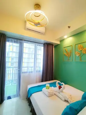 a bedroom with a bed with towels and a window at The Barn at Sea Residences in Manila