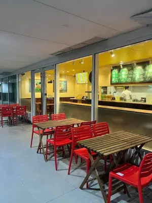 a restaurant with wooden tables and red chairs at The Barn at Sea Residences in Manila