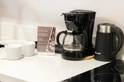 a coffee maker and two cups on a counter at The Place To Be with Balcony and Kitchen Mandaluyong in Manila