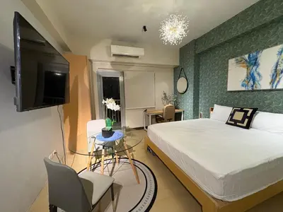 a bedroom with a large bed and a tv at The Ellis Luxe Suites in Manila