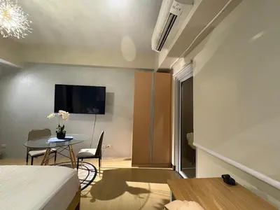 a room with a bed and a table and a tv at The Ellis Luxe Suites in Manila