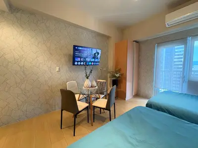 a bedroom with a table and a tv on a wall at The Ellis Luxe Suites in Manila