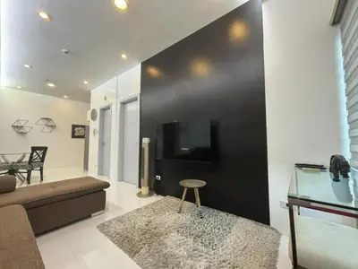 a living room with a couch and a tv on a wall at 8 Adriatico Condominium in Manila
